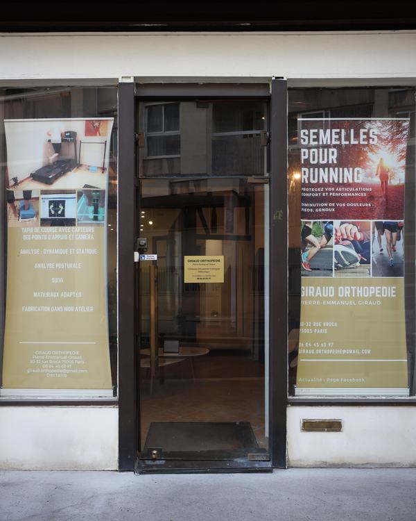 Façade vitrée du cabinet Giraud Orthopédie, 30-32 rue Broca à Paris 5ᵉ, avec ses affiches « Semelles pour running ».